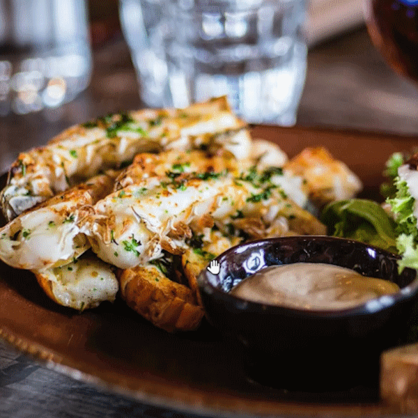 A plate of beautifully-spiced seafood with greens
                    and a dipping sauce